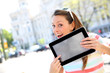 Cheerful girl in town showing tablet screen