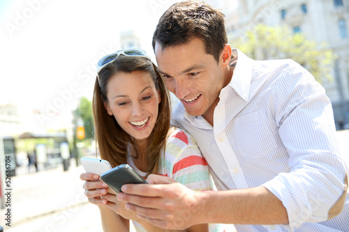Photo: Couple of tourists in Madrid using smartphone Couple of tourists in Madrid using smartphone