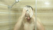 Young man washing his hair and face in shower
