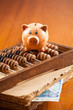 Piggy bank on an old abacus, old book,  and 20 euro banknote