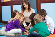 Teacher And Students Reading Book In Preschool