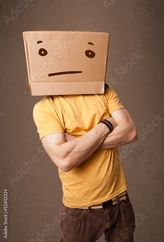 Photo: Young man gesturing with a cardboard box on his head with straig Young man gesturing with a cardboard box on his head with straig