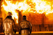 Firefighters at burning fire flame on wooden house roof