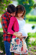 young pregnant couple in blooming park