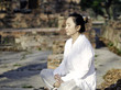Asian woman meditating in ancient buddhist temple