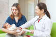 doctor examining newborn baby on mother's arms