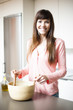 Portrait of young happy woman making salad at domestic kitchen