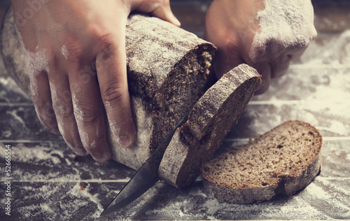 Photo: Male hands slicing home-made bread Male hands slicing home-made bread