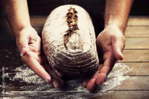 Photo: Baker's hands with a bread Baker's hands with a bread