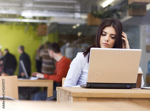 Photo: Pensive young beautiful businesswoman sitting at desk Pensive young beautiful businesswoman sitting at desk