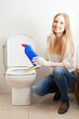 Smiling long-haired woman cleaning toilet