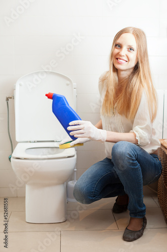 Photo: Smiling long-haired woman cleaning toilet Smiling long-haired woman cleaning toilet