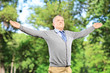 Happy gentleman spreading his arms in a park