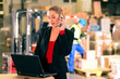 Frau mit Telefon in Lagerhalle einer Spedition