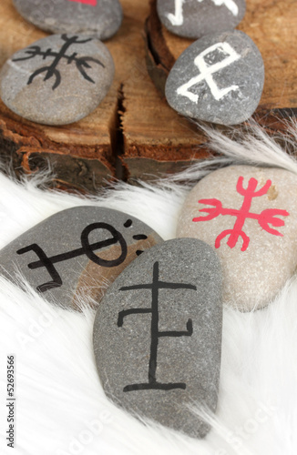 Photo: Fortune telling with symbols on stones on white fur background Fortune telling with symbols on stones on white fur background