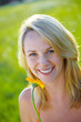 Beautiful blond girl in summer with flower