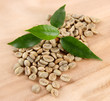 Green coffee beans and leaves on wooden background