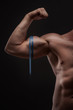 man measures his biceps with measuring tape