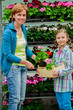 Mother with daughter shopping plants and flowers in garden cente