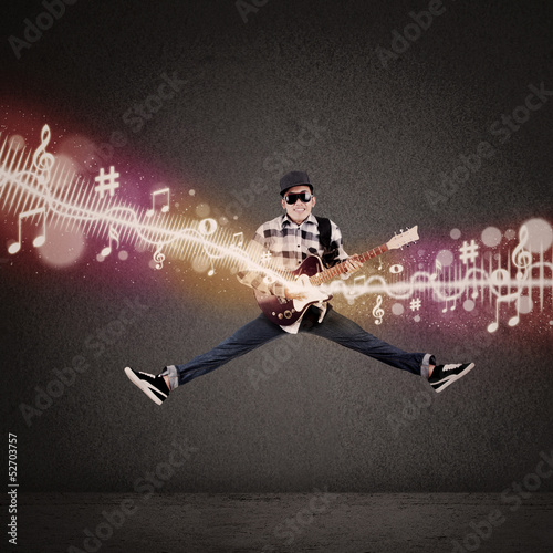 Photo: Acrobatic guitarist jumping with musical notes Acrobatic guitarist jumping with musical notes