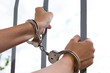 Handcuffed hands holding bars
