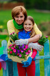 Gardening- lovely girl with mother working in flowers garden