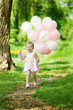 Small caucasian plays in summer park with colorful baloons