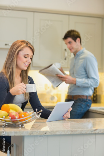 Photo: Woman with beverage and tablet computer and man with newspaper Woman with beverage and tablet computer and man with newspaper