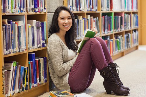 Photo: Student in a library leaning against a shelf Student in a library leaning against a shelf