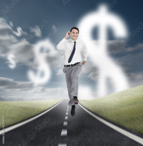 Photo: Businessman running on a road with dollars floating Businessman running on a road with dollars floating
