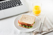 Having a sandwich and an orange juice as a snack while working