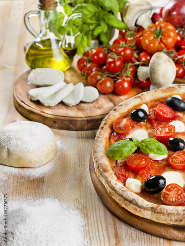 Photo: Italian pizza with tomato, mozzarella, basil and olives Italian pizza with tomato, mozzarella, basil and olives