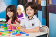 Boy With Blocks While Friends Playing In Background