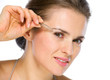 Beauty portrait of young woman using tweezers