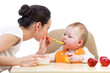 young mother spoon feeding her baby girl