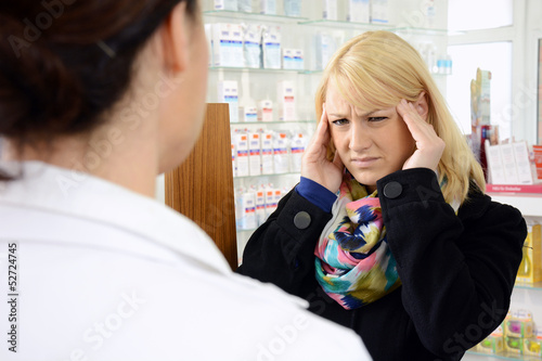 Photo: Frau mit Kopfschmerzen in Apotheke Frau mit Kopfschmerzen in Apotheke