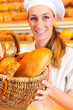 Female baker selling bread by basket in bakery