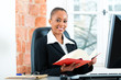 Lawyer in her office with law book on computer