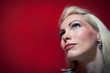 Photo: Blonde woman close up portrait against red wall background. Blonde woman close up portrait against red wall background.