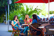 young female friends sitting on cafe terrace, urban outdoors