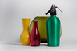Still life of red bottle yellow vase and green seltzer siphon