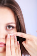 Young woman putting contact lens in her eye close up