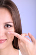 Young woman putting contact lens in her eye close up