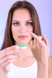 Young woman putting contact lens in her eye close up