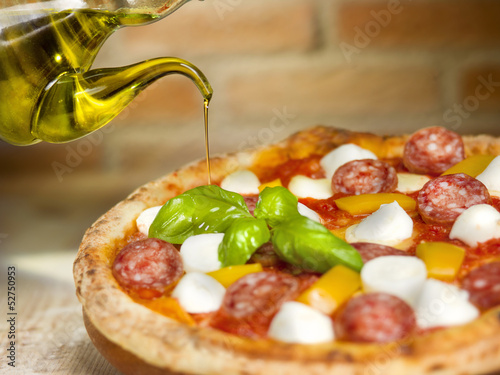 Photo: Italian pizza with tomato, mozzarella, peppers salami and basil Italian pizza with tomato, mozzarella, peppers salami and basil