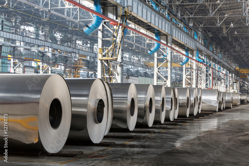 Photo: Row of rolls of aluminum lie in production shop of plant. Row of rolls of aluminum lie in production shop of plant.