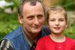Granddaughter in red dress with her grandfather in nature.