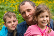 Grandfather, granddaughter and grandson smiling in nature.