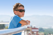 Portrait of boy stands on balcony of hotel and looks