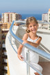 A girl stands on the balcony of hotel on background of cityscape